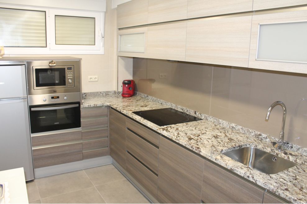 Cocina bicolor con encimera de granito y entrepaño de cristal - A.Z
